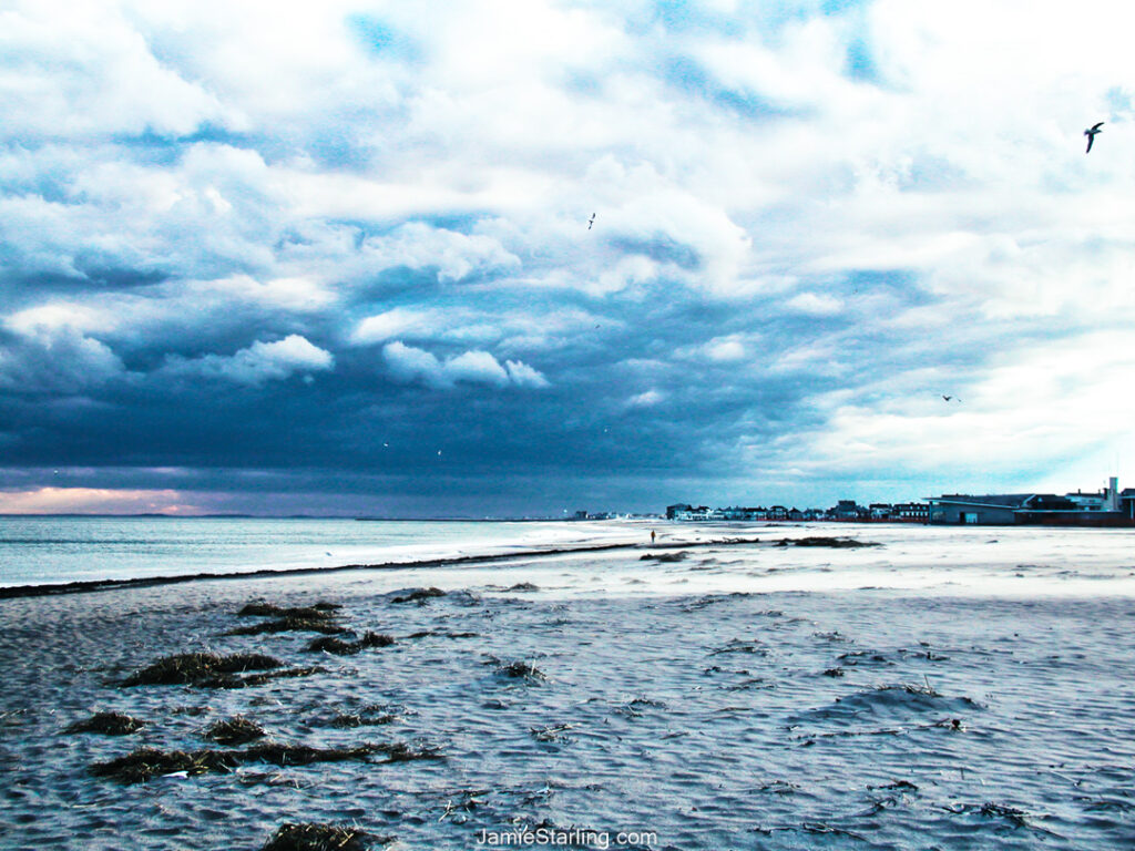 A winter scene at Hampton Beach, New Hampshire, showcasing stormy skies and a peaceful shoreline, inviting reflection and calm.